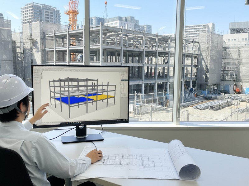 モニターに映した建物の3Dモデルを回して、柱と梁の位置を確かめている人